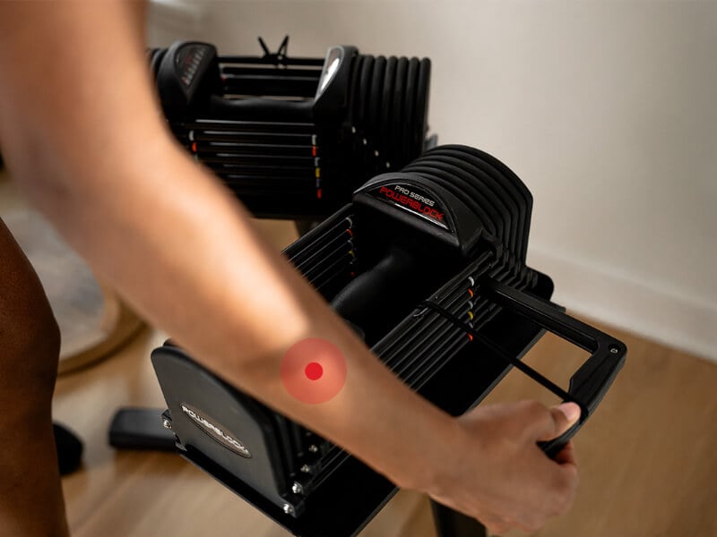 Woman showing how to use the selector pin to adjust the weight on the PowerBlock Pro 32.